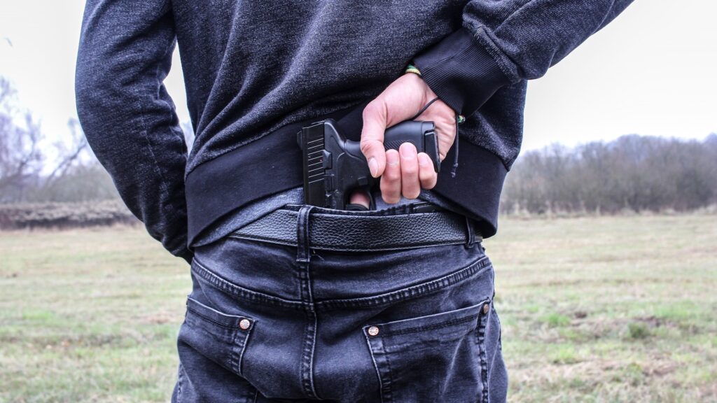 A man pulls a handgun from his waistband.