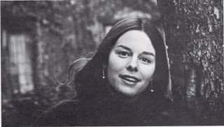Portrait of Jane Mickelson as a young woman. She has long brown hair and is smiling and looking directly into the camera.