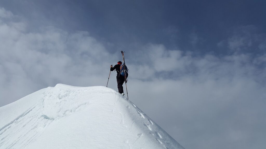 A backcountry skier hikes to the top of a mountain.