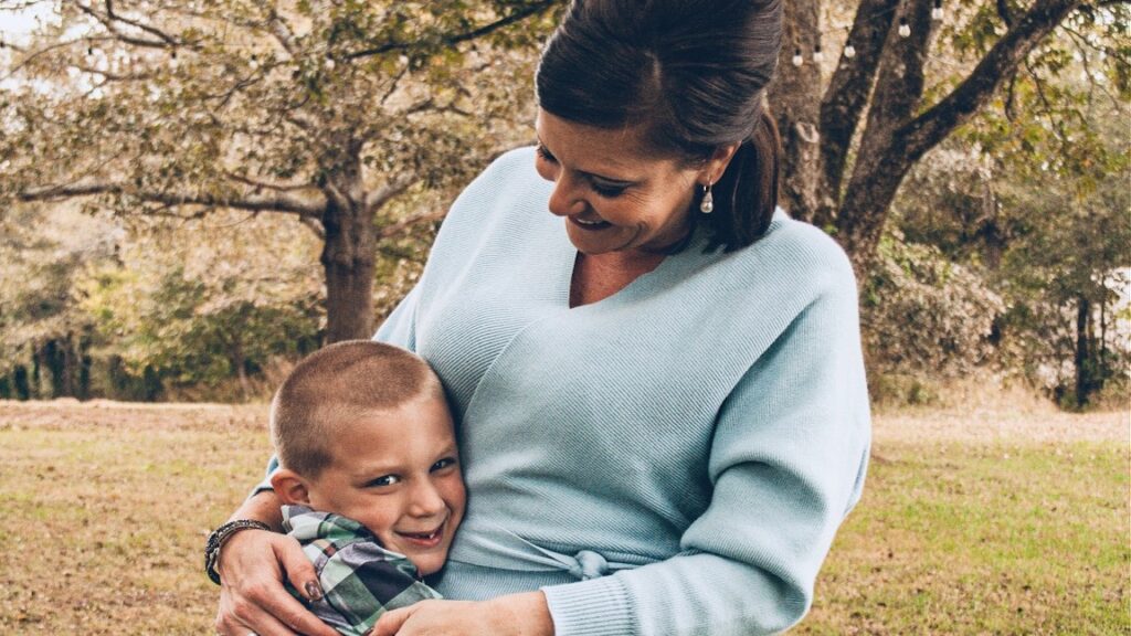 A woman embraces a child. They are both smiling joyfully.