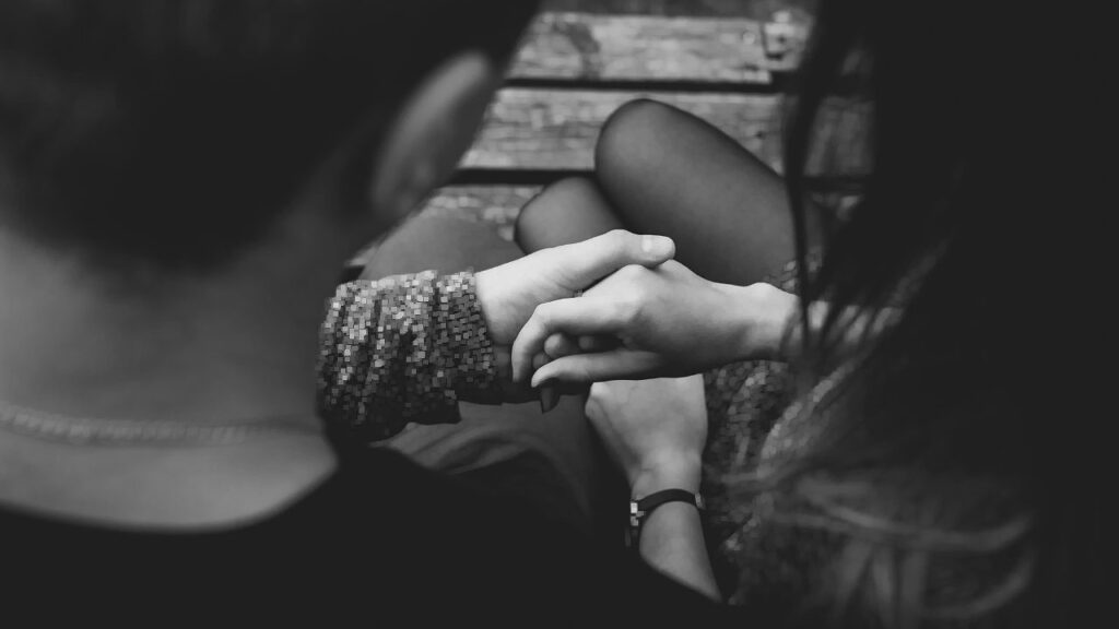 A closeup of two people's hands, clasping each other, as seen between their two heads.