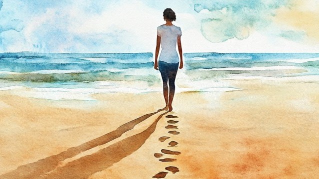 A woman walks down a beach on a sunny day, leaving footprints in the sand behind her.